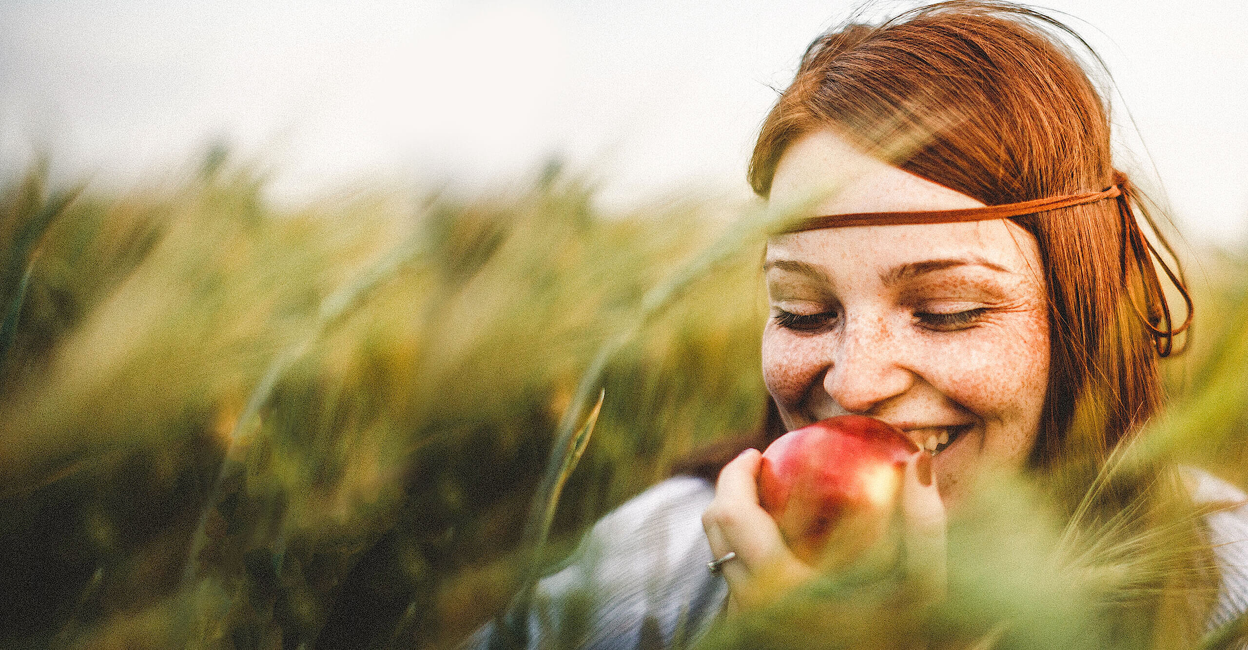 Foto von Frau in der Natur. Sie hält einen Apfel und genießt den Augenblick.